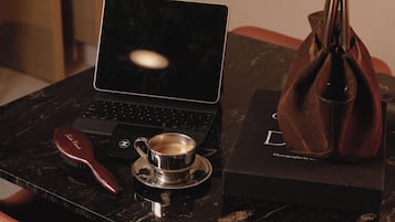 A laptop on a marble table, a cup of coffee, a hairbrush, and a handbag.