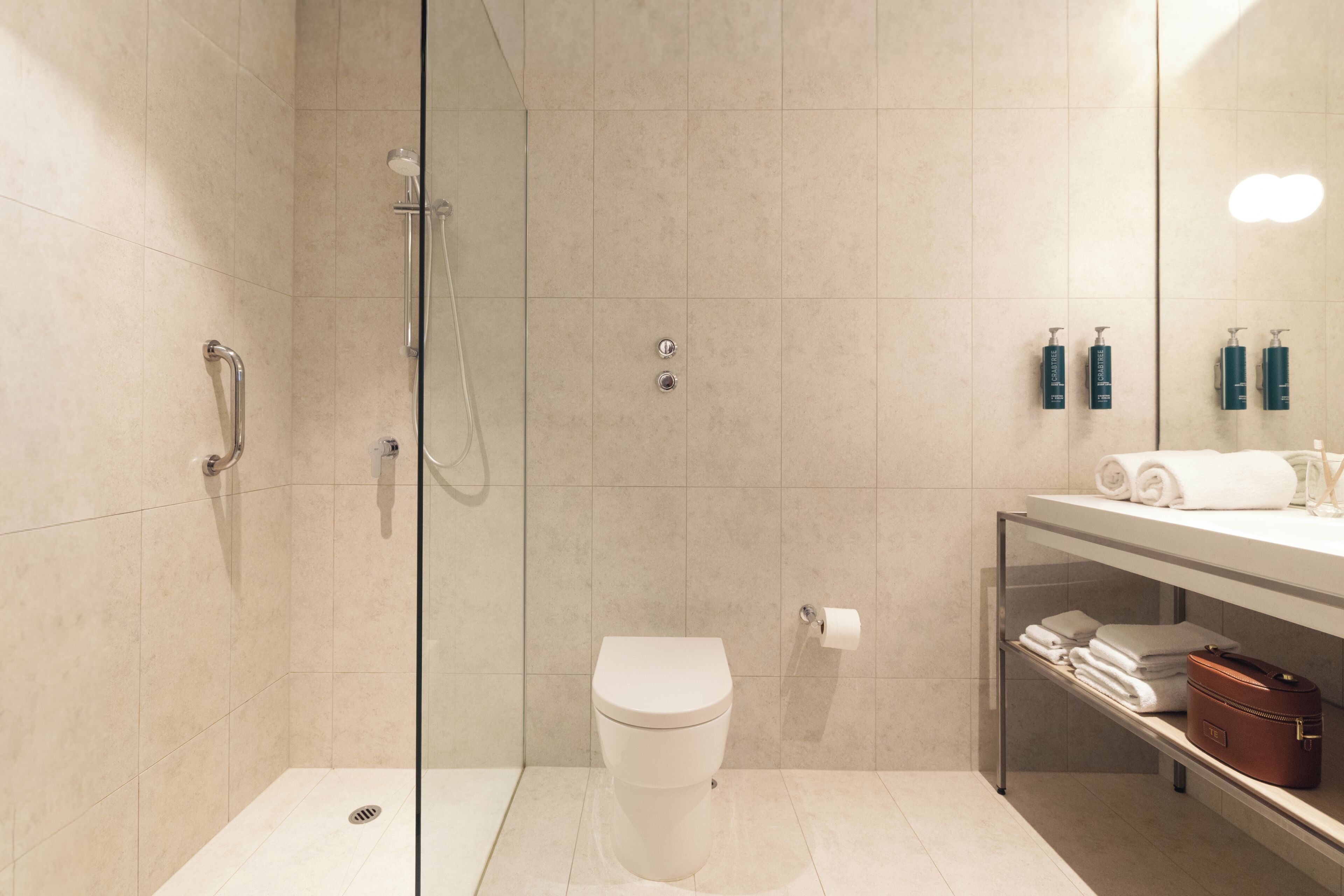 A modern bathroom with a glass-enclosed shower, a toilet, and a vanity with toiletries.
