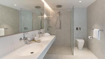 A modern bathroom with a glass-enclosed shower, a white sink, and a toilet.