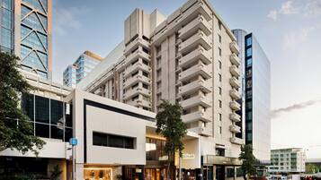 A modern hotel with a prominent corner entrance, a visible Hilton sign, and a large glass facade.