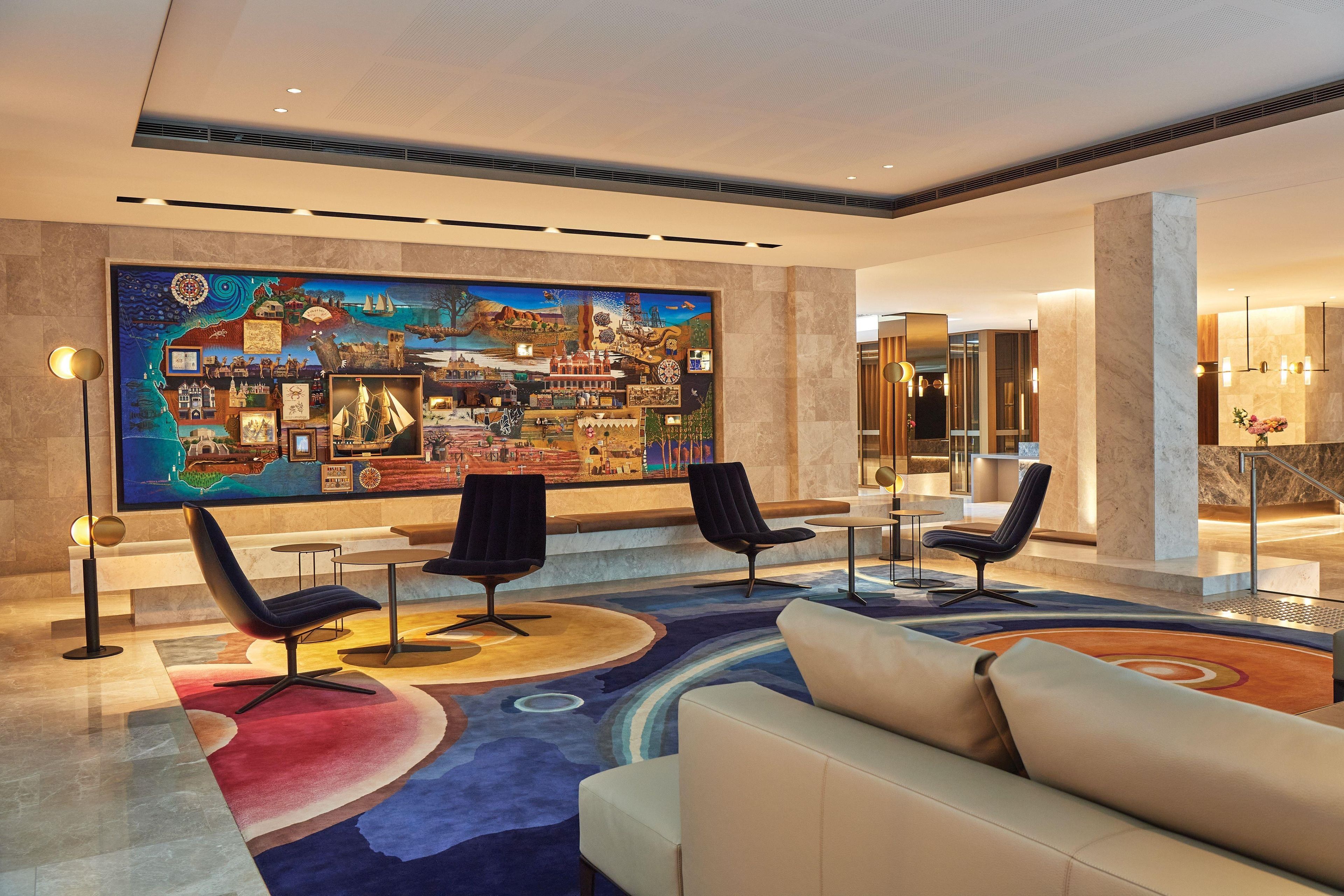 A lobby with a large mural, seating area, and a reception desk.