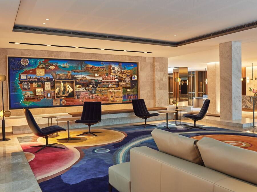 A lobby with a large mural, seating area, and a reception desk.