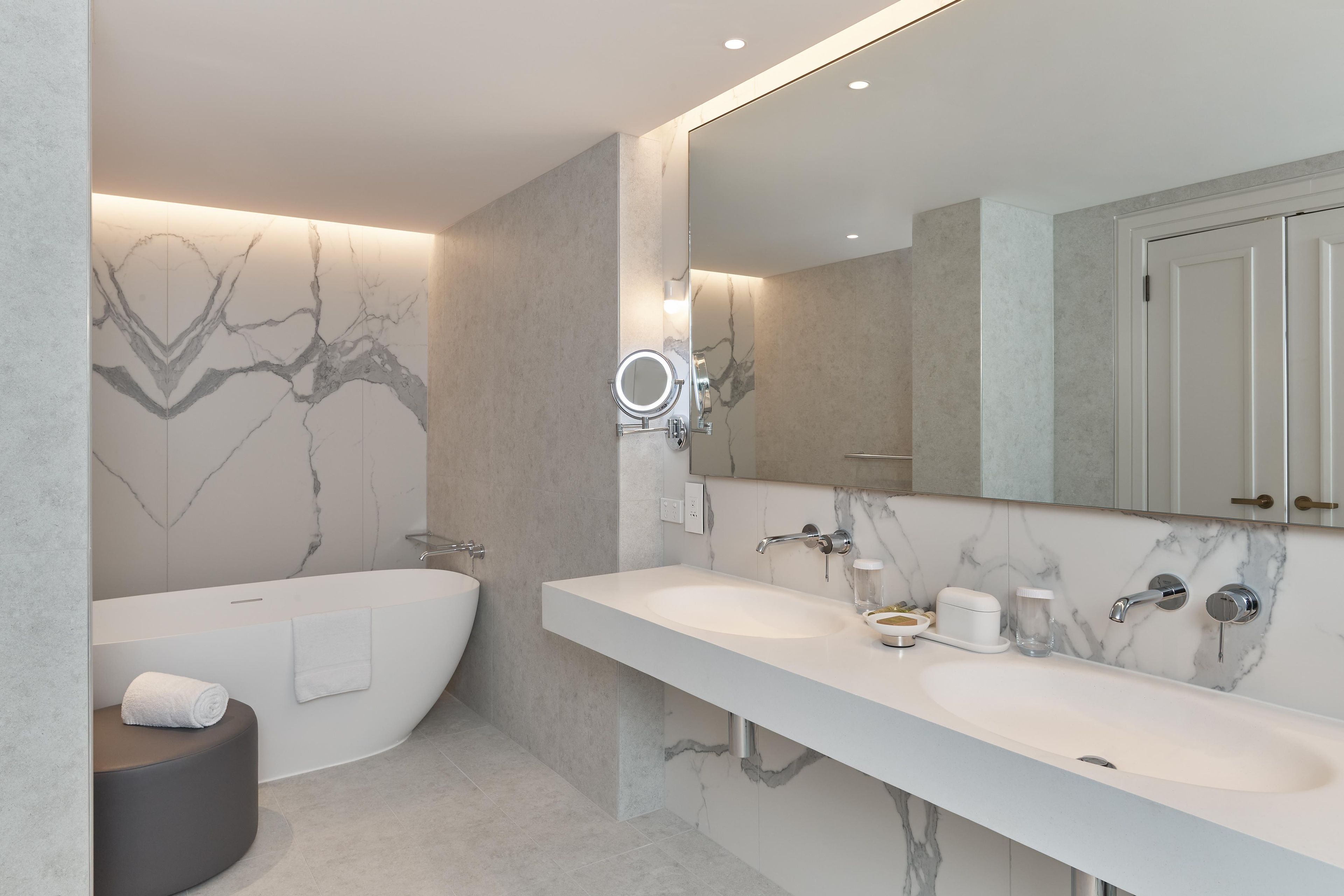 Un baño moderno con bañera, dos lavamanos, tocador y un espejo grande.