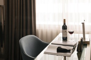 A modern hotel room with a glass table, a wine bottle, and a glass of red wine.
