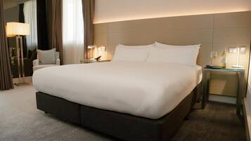 A hotel room with a large bed, bedside tables, a lamp, and a wine bottle.