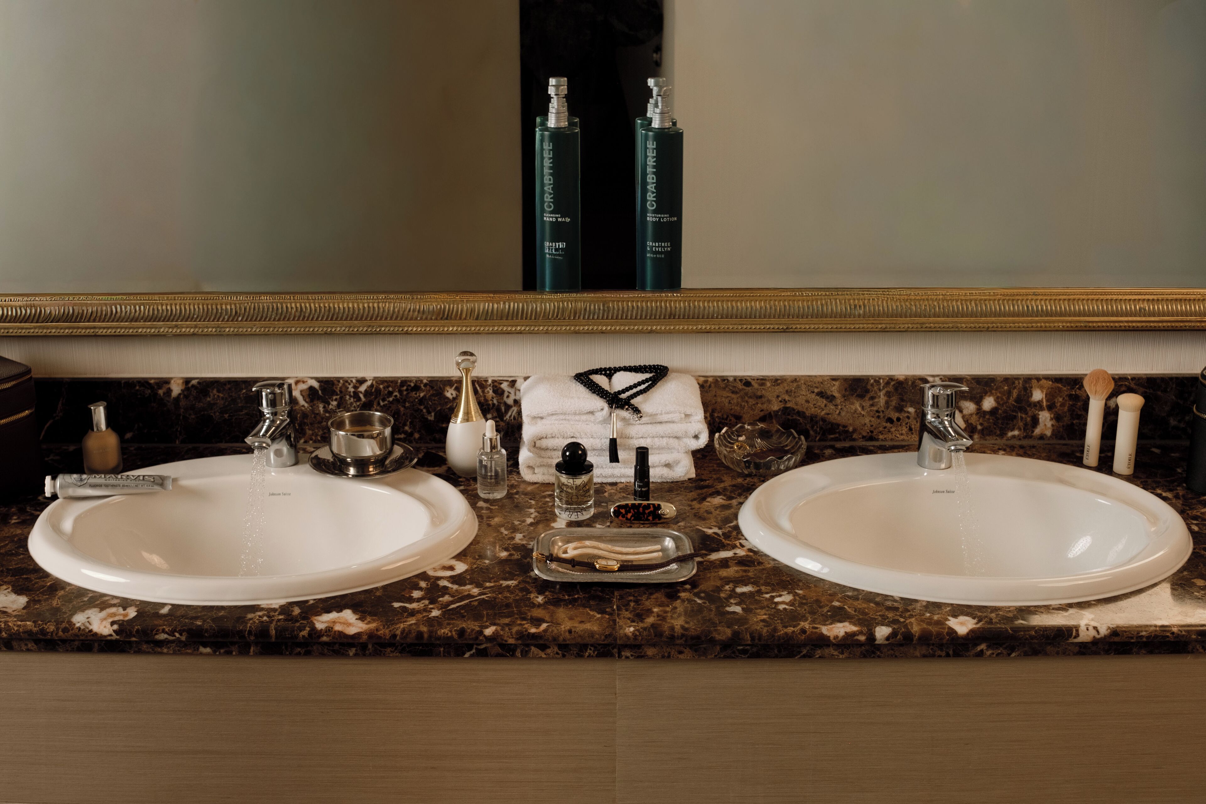 Une salle de bain avec deux lavabos, un miroir et des articles de toilette.
