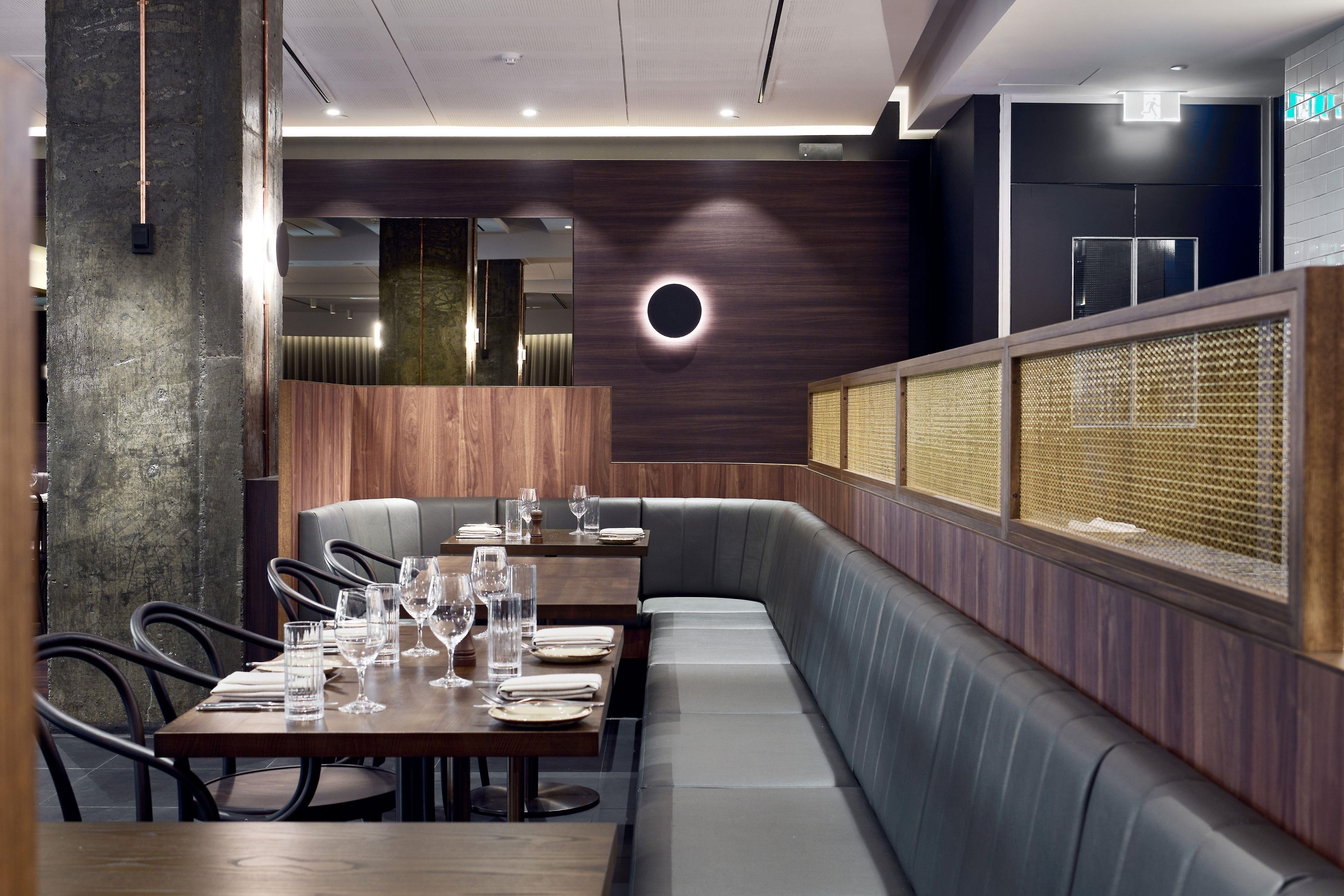 A restaurant interior with wooden paneling, cushioned seating, and a modern design.