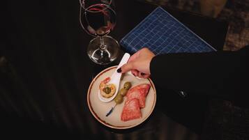 Una taula de menjador amb un plat de menjar, una copa de vi i un gots blau.