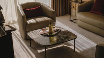 A modern living room with a leather sofa, a leather armchair, a marble coffee table with a bottle and glass, and a small side table.
