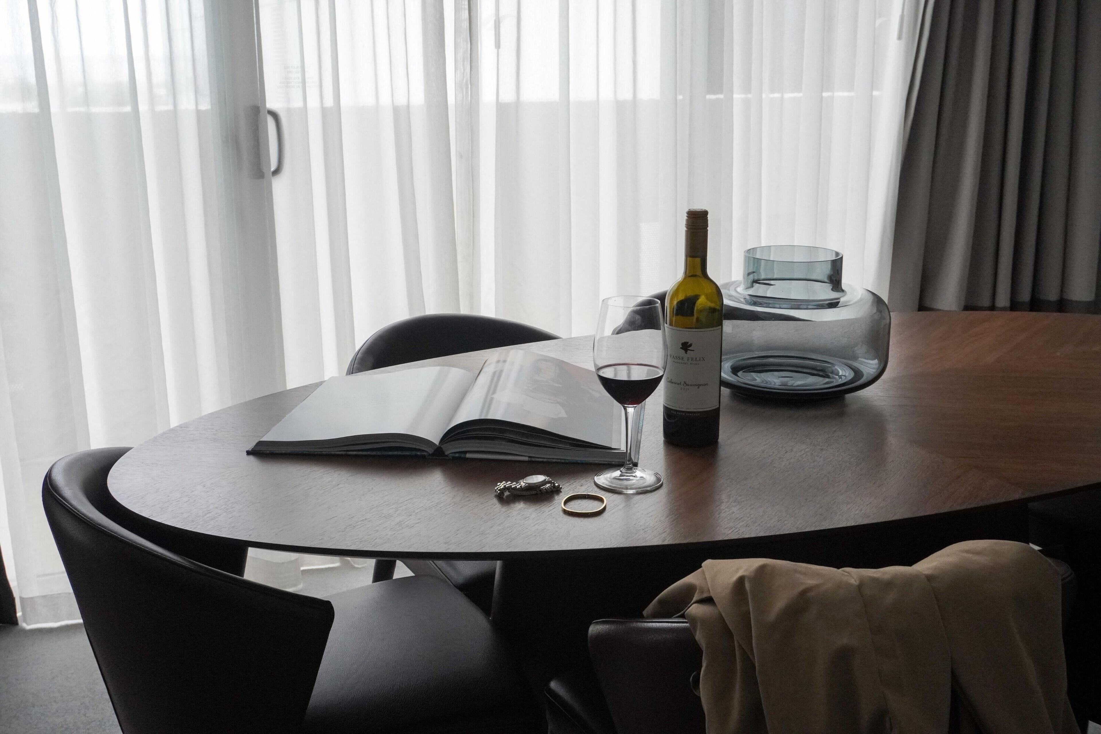 A round table with a book, a wine bottle, and a glass.