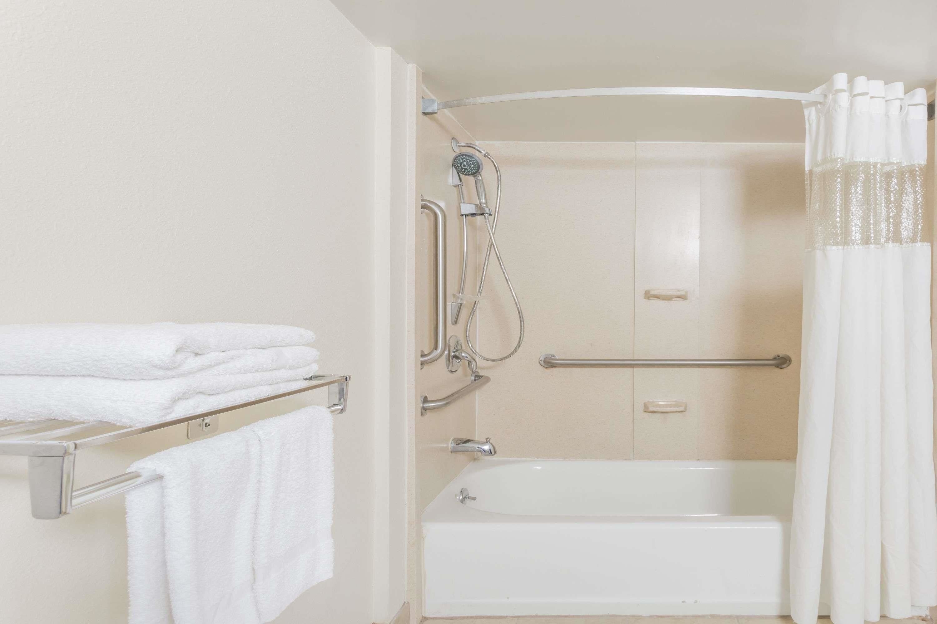 A bathroom with a bathtub, a shower, and a towel rack with folded towels.