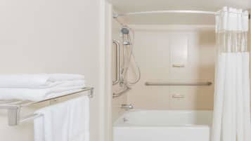 A bathroom with a bathtub, a shower, and a towel rack with folded towels.