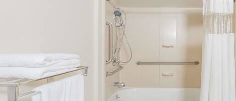 A bathroom with a bathtub, a shower, and a towel rack with folded towels.