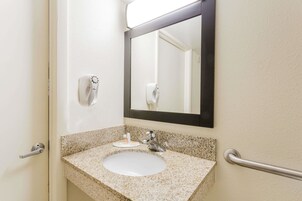 Baño con lavamanos de encimera de granito, espejo, secamanos y dispensador de jabón.