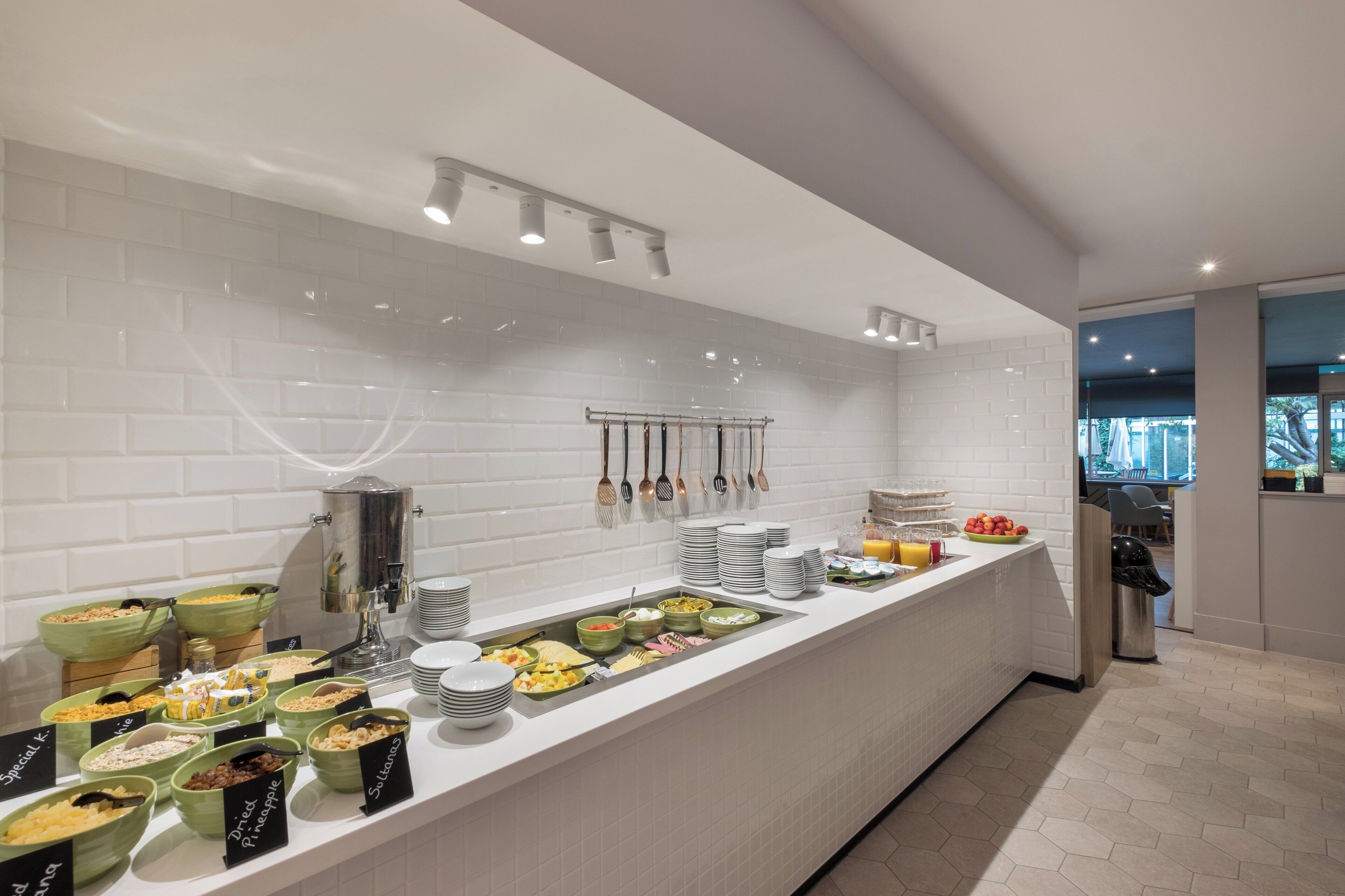 Un buffet proposant divers plats et ustensiles, une machine à café et un grand récipient isotherme pour le café.