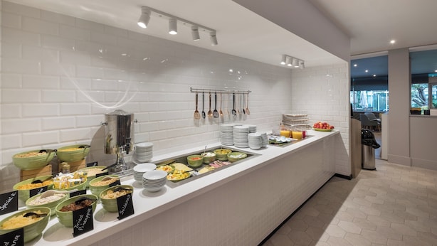 A buffet with various food items and utensils, a coffee machine, and a coffee urn. - Holiday Inn Swindon by IHG (Swindon)