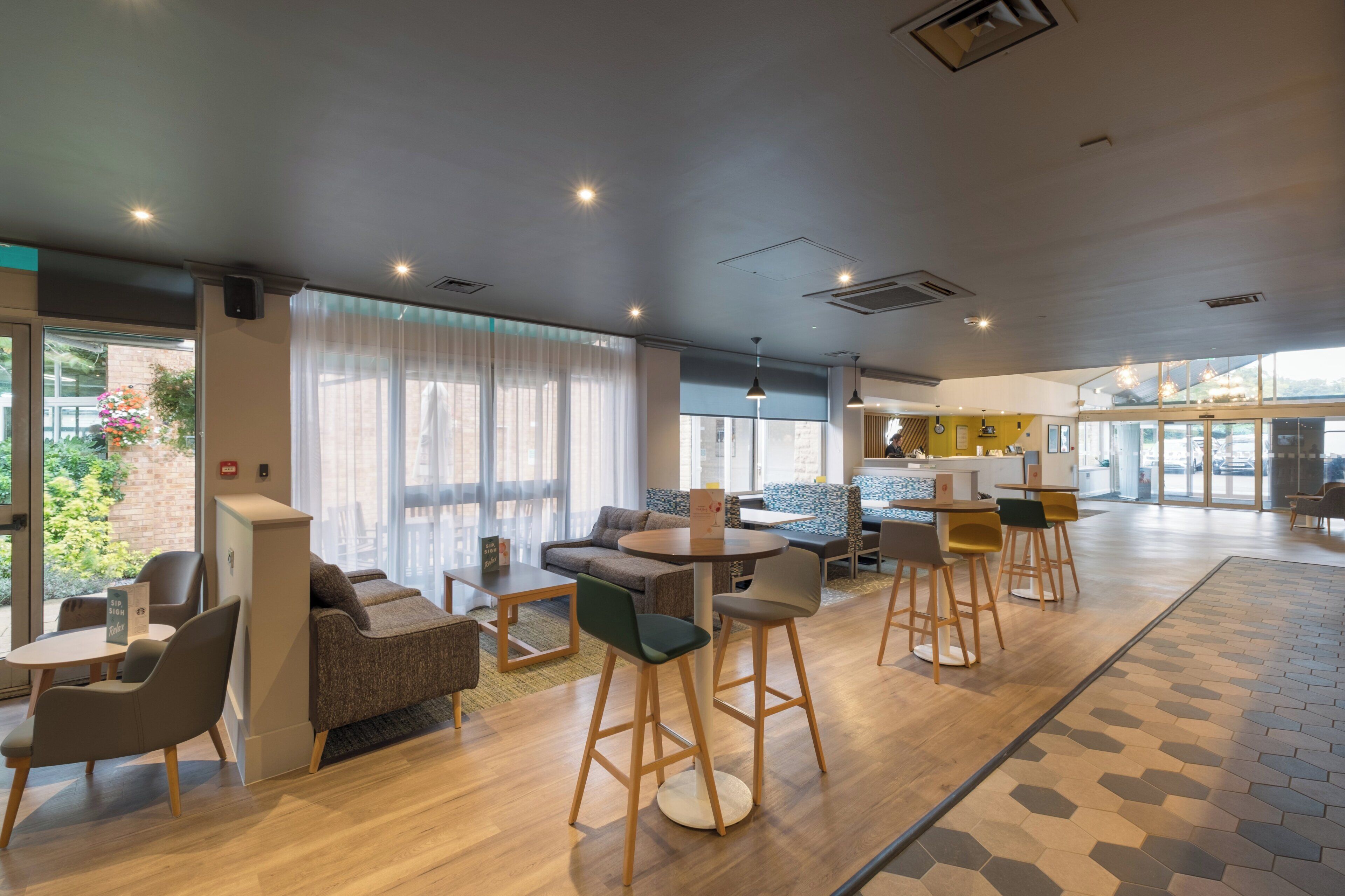 A modern hotel lobby with seating areas, a reception desk, and large windows.