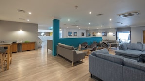 A modern hotel lobby with a reception desk, seating area with sofas and chairs, and a large window providing natural light. - Holiday Inn Swindon by IHG (Swindon)