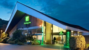 A Holiday Inn hotel with a modern design, featuring a prominent green logo and a stone facade.