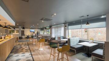 A modern interior with a reception desk, seating areas, and large windows.