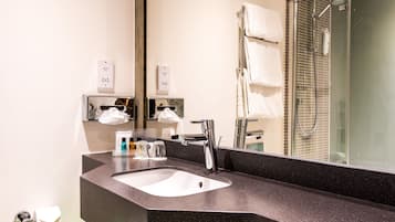 Une salle de bain moderne avec un lavabo en granit noir, un grand miroir et une cabine de douche en verre.
