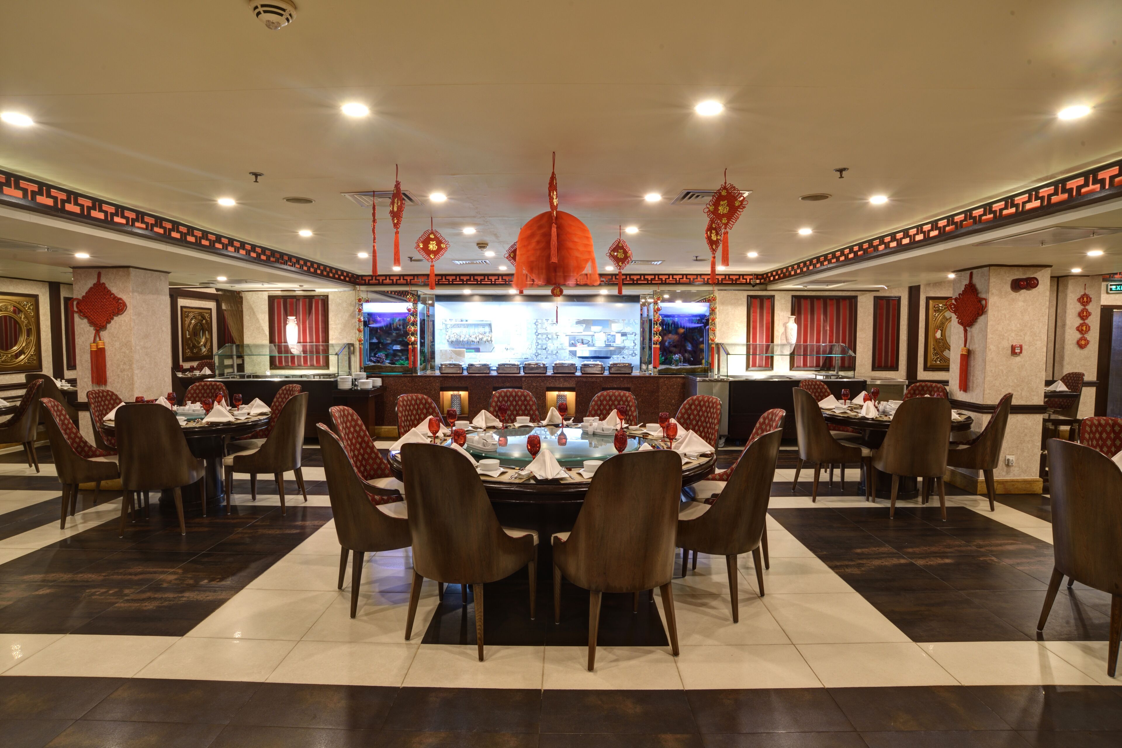 A restaurant with round tables, red and brown chairs, and red lanterns.