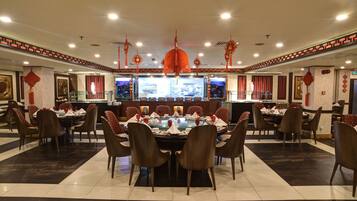 A restaurant with round tables, red and brown chairs, and red lanterns.