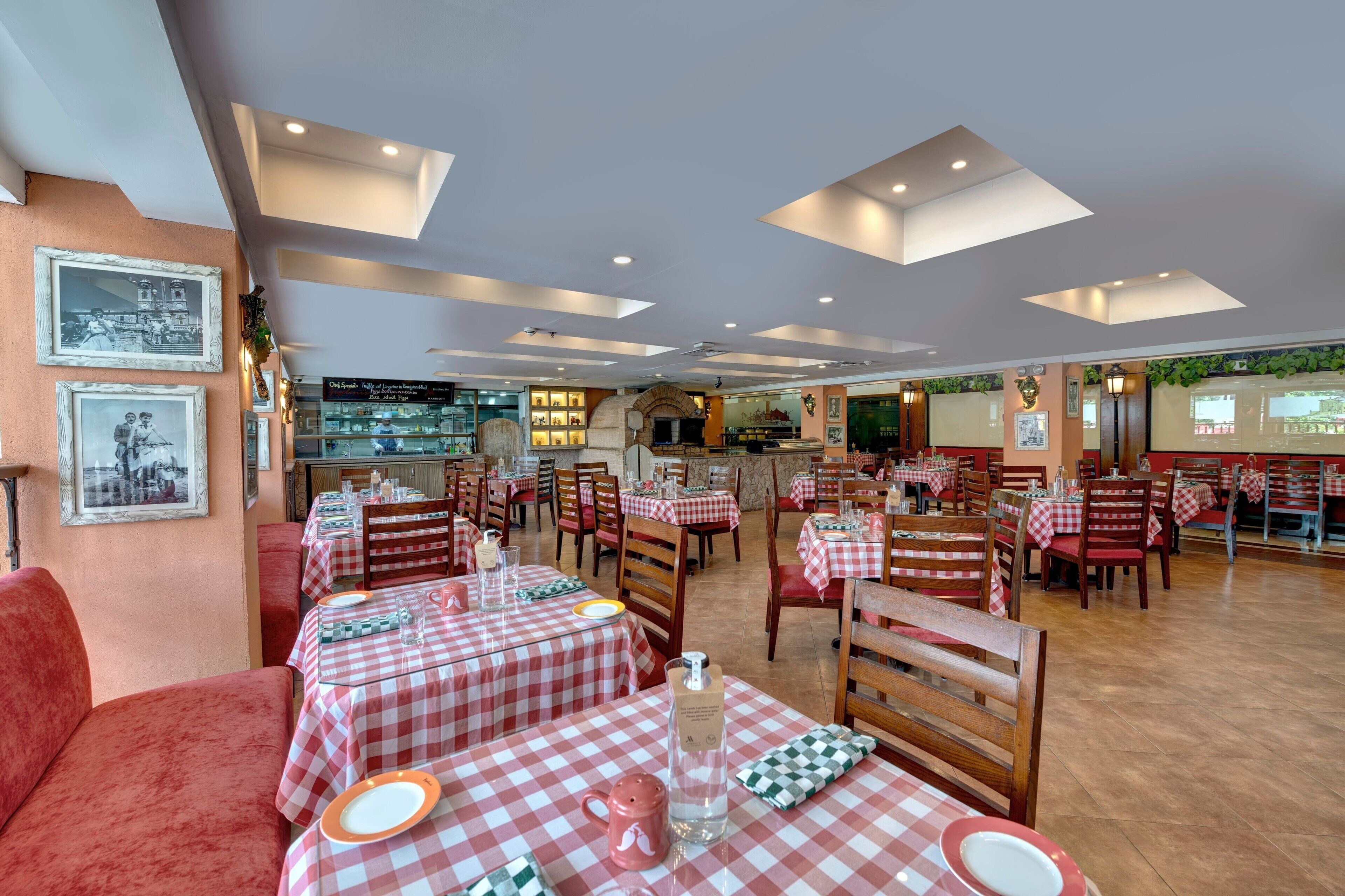 Un restaurante con manteles a cuadros, sillas de madera y un sofá rojo.