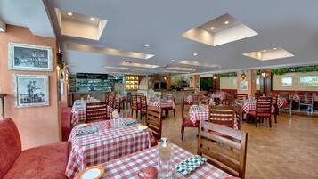 Un restaurante con manteles a cuadros, sillas de madera y un sofá rojo.