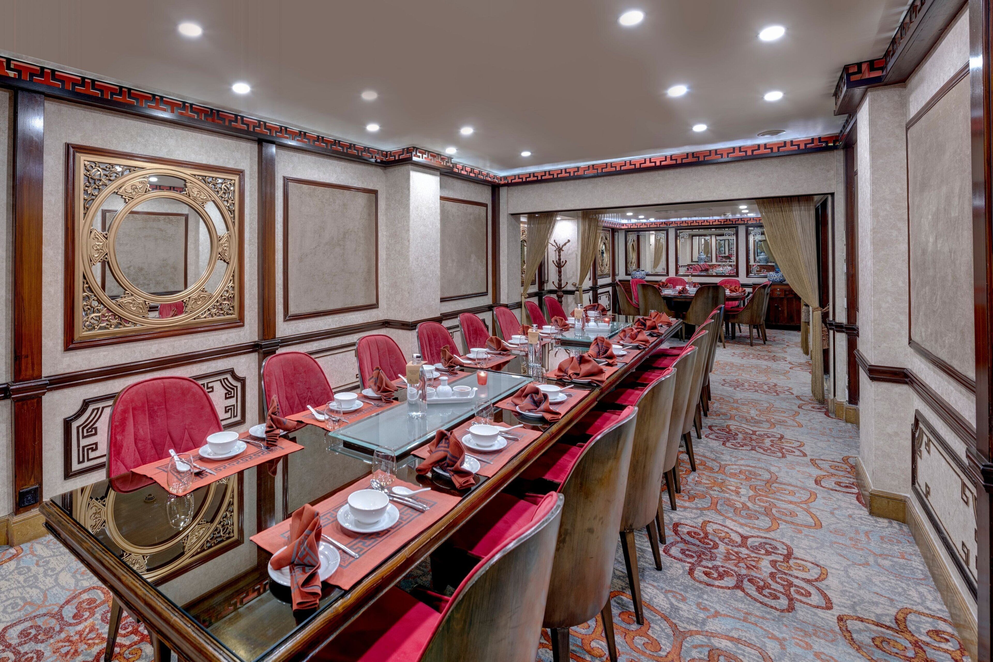 A conference room with a long table, red chairs, and a patterned carpet.