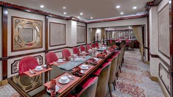 A conference room with a long table, red chairs, and a patterned carpet.