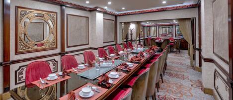 A conference room with a long table, red chairs, and a patterned carpet.