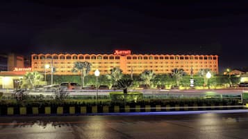 Un hotel Marriott con una estructura de varios pisos, un estacionamiento y una entrada bien iluminada.