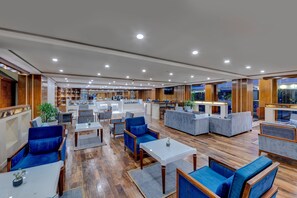 A spacious lobby with wooden flooring, blue upholstered seating, and a central bar area. - Islamabad Marriott Hotel (Islamabad)
