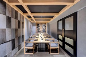 Une salle de conférence avec une longue table, des chaises et un grand tableau abstrait accroché au mur.