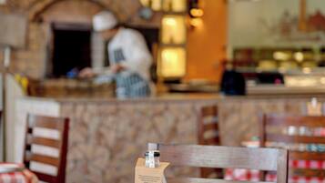 A restaurant interior with a checkered tablecloth, glasses, a mug, and a bottle on the table.