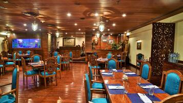 Un restaurant avec des planchers en bois et des chaises à revêtement bleu. Les tables sont dressées avec des sets de table bleus et de la verrerie assortie.