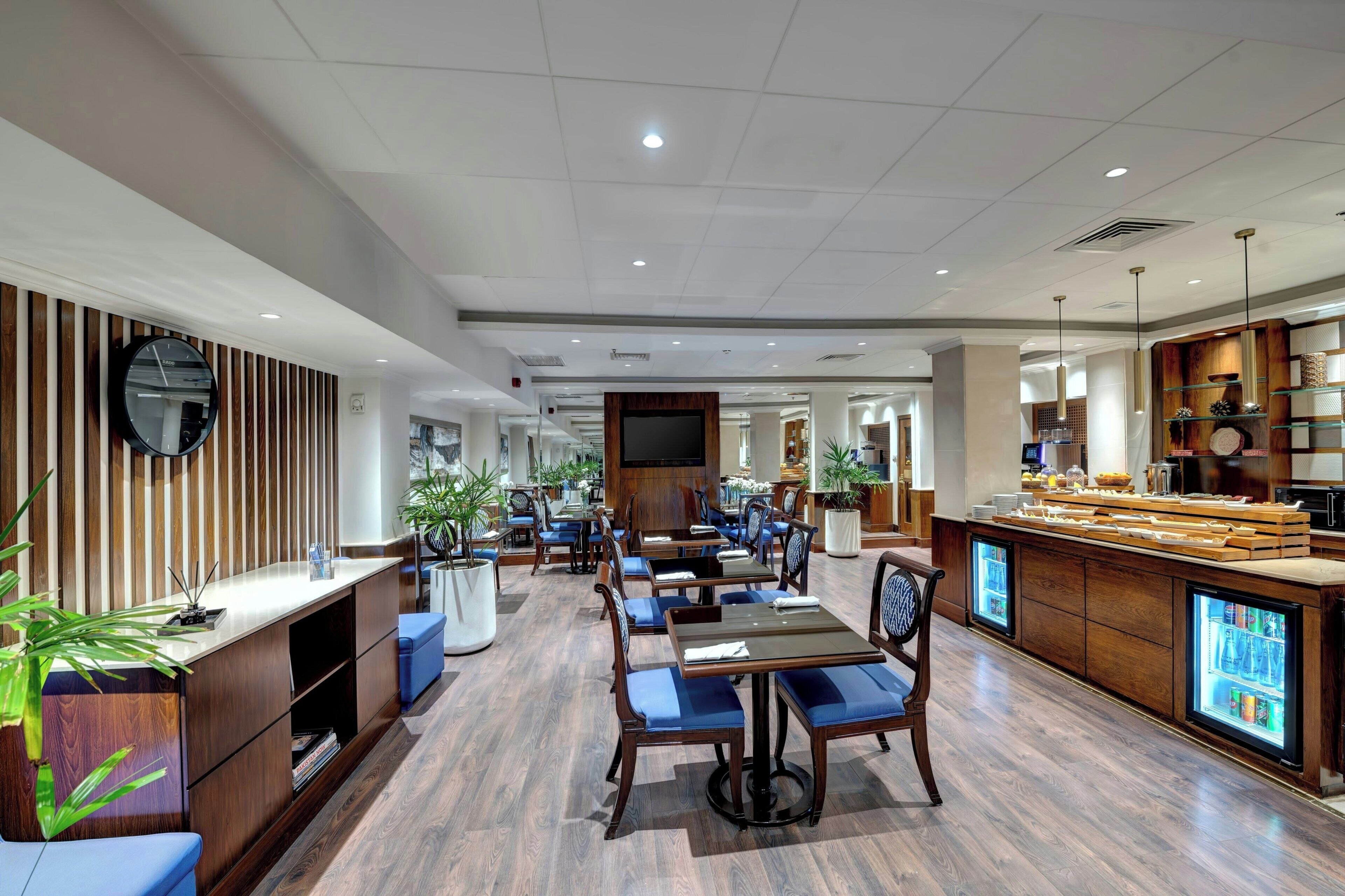 A modern hotel lobby with wooden paneling, a reception desk, seating areas, and a bar.