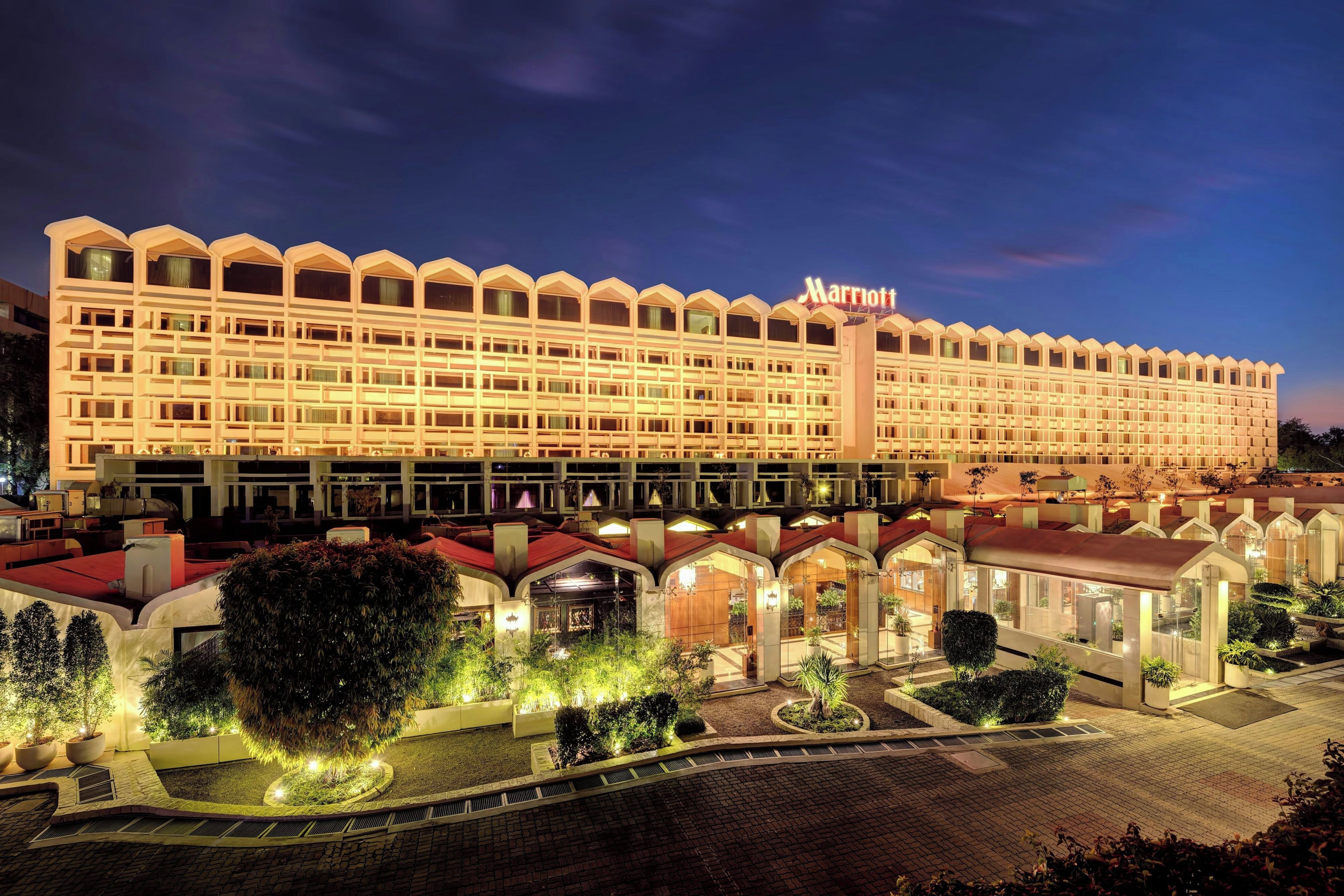 Um hotel grande, com vários andares, apresentando uma cobertura arqueada característica e um letreiro 'Marriott' bem visível.