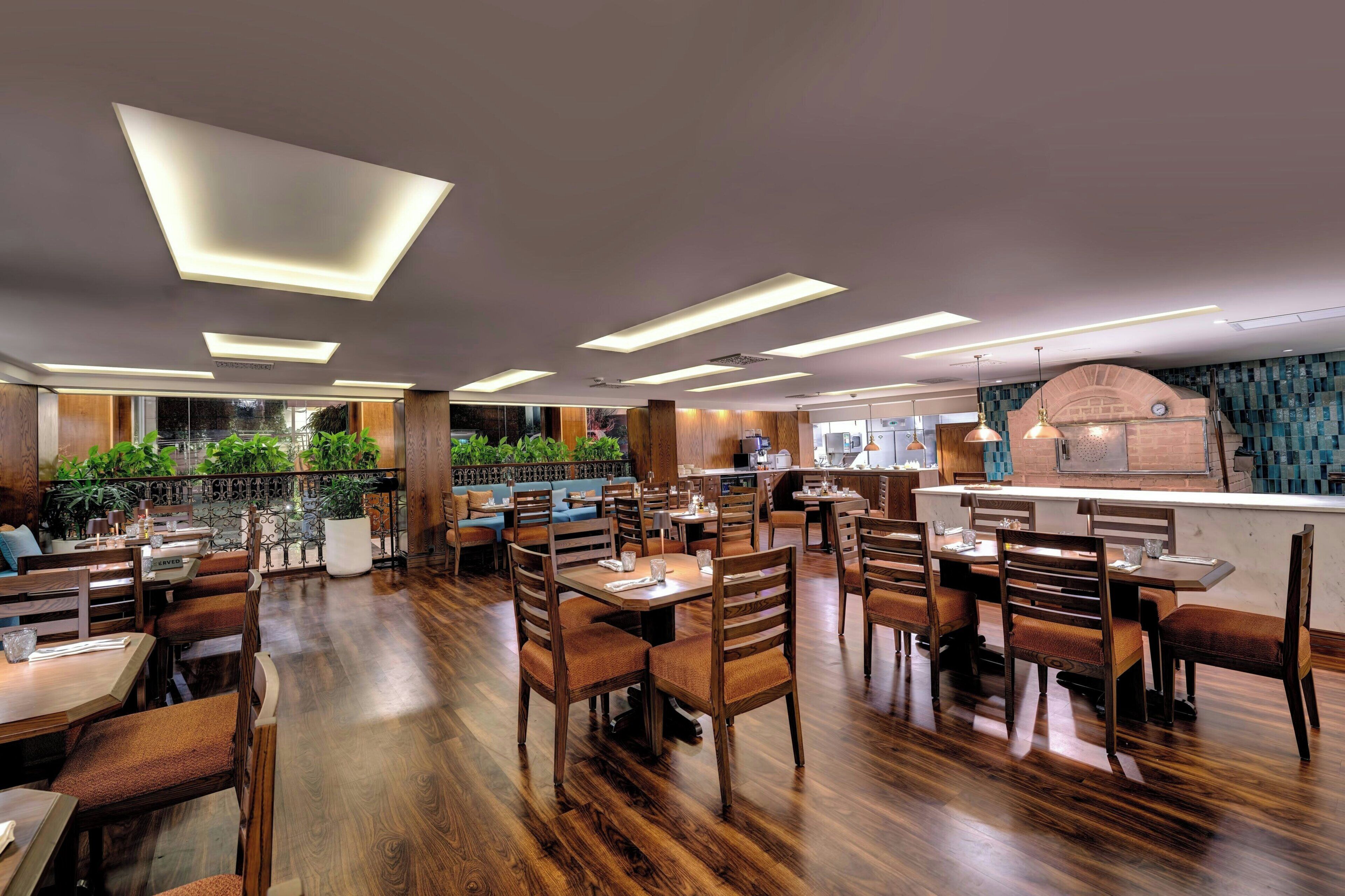 A restaurant with wooden flooring, modern lighting, and a brick oven.