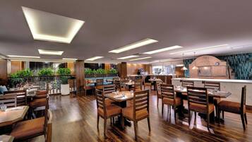 A restaurant with wooden flooring, modern lighting, and a brick oven.