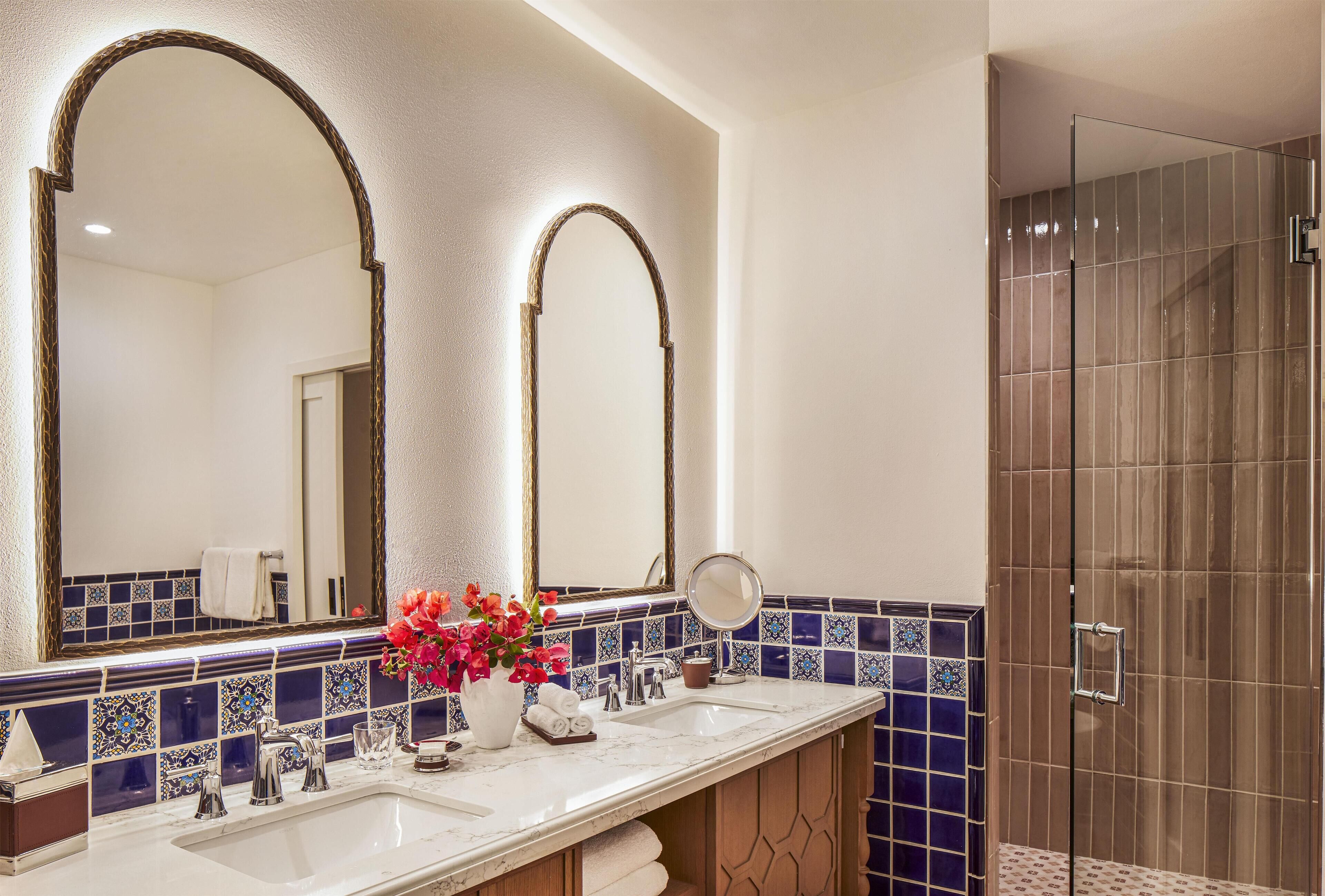 Een badkamer met een grote spiegel, een wastafel en een douchehoek.