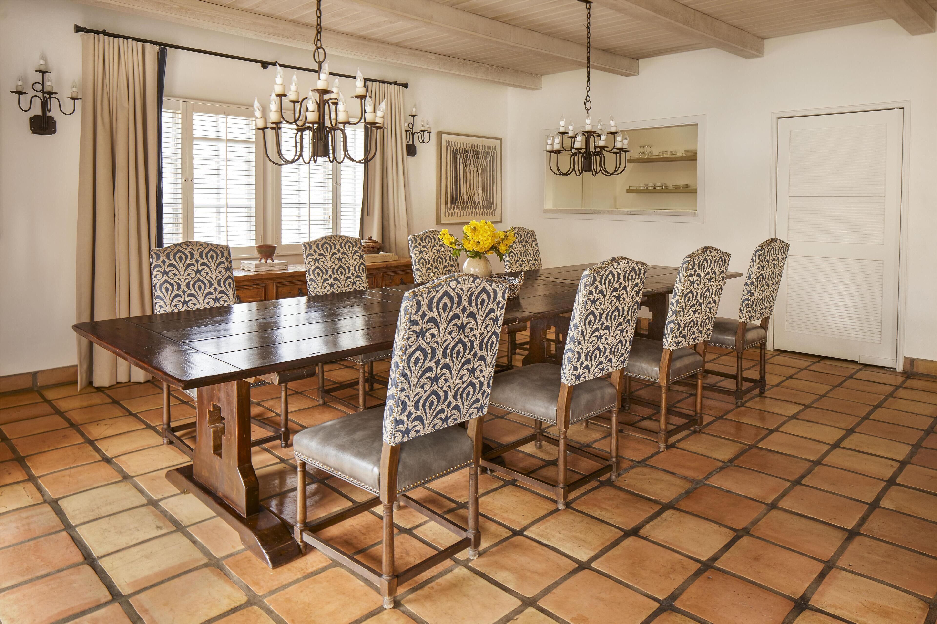 Une salle à manger avec une grande table en bois, des chaises à motifs et un lustre.