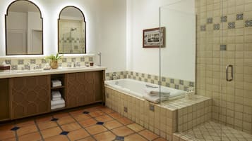 A bathroom with a bathtub, a shower, and a vanity with a mirror.