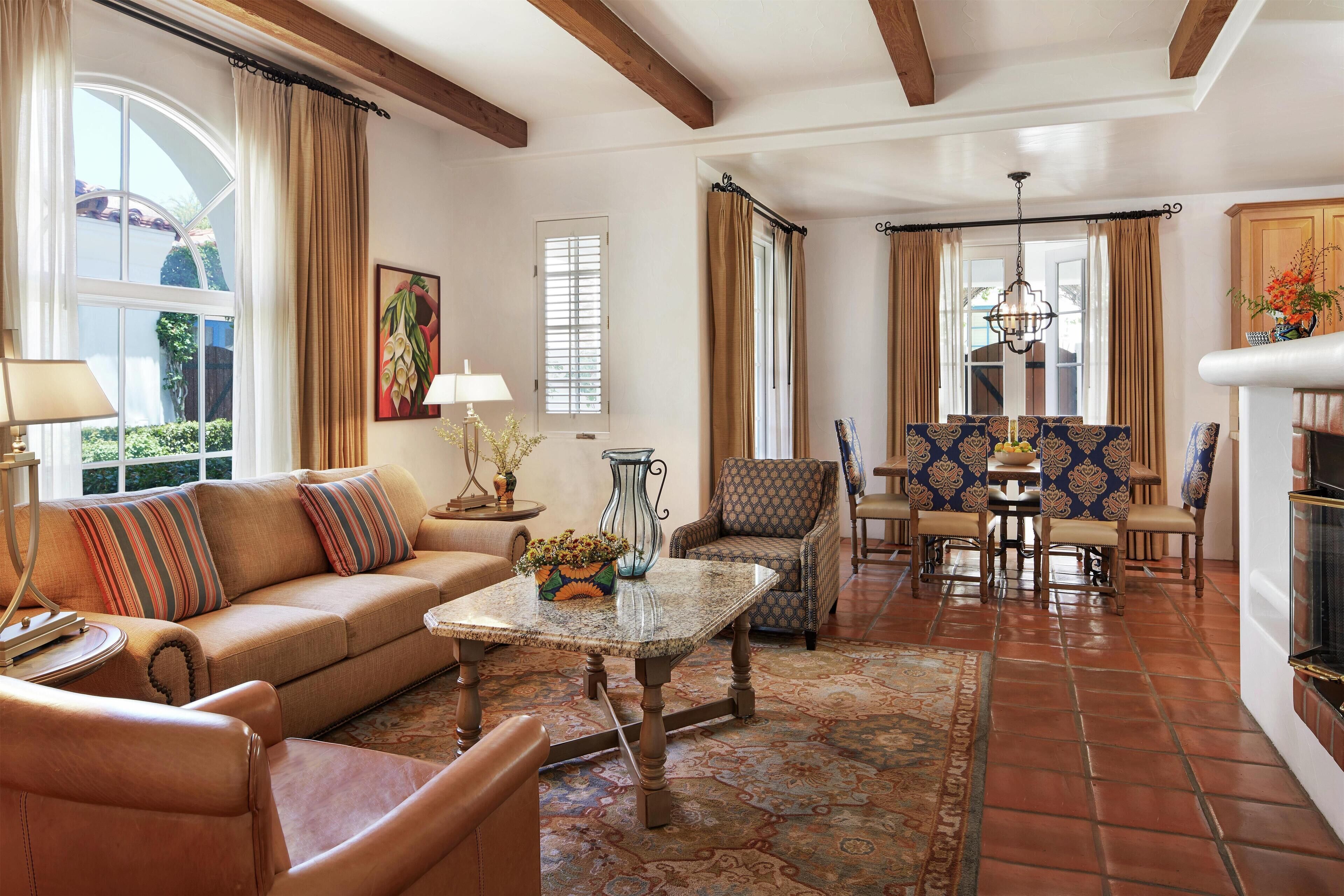 A living room with a sofa, armchairs, a coffee table, and a dining area with chairs and a table.