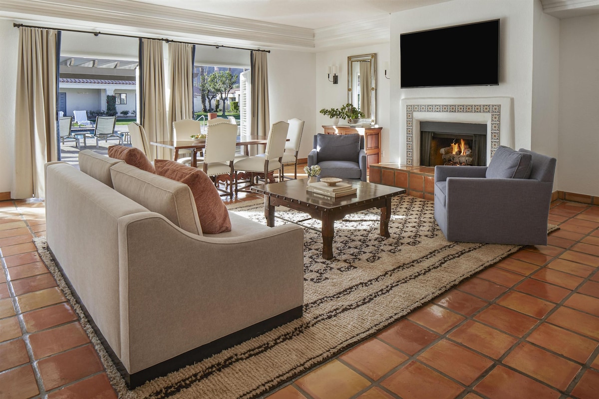 A living room with a sofa, armchairs, a coffee table, and a fireplace.
