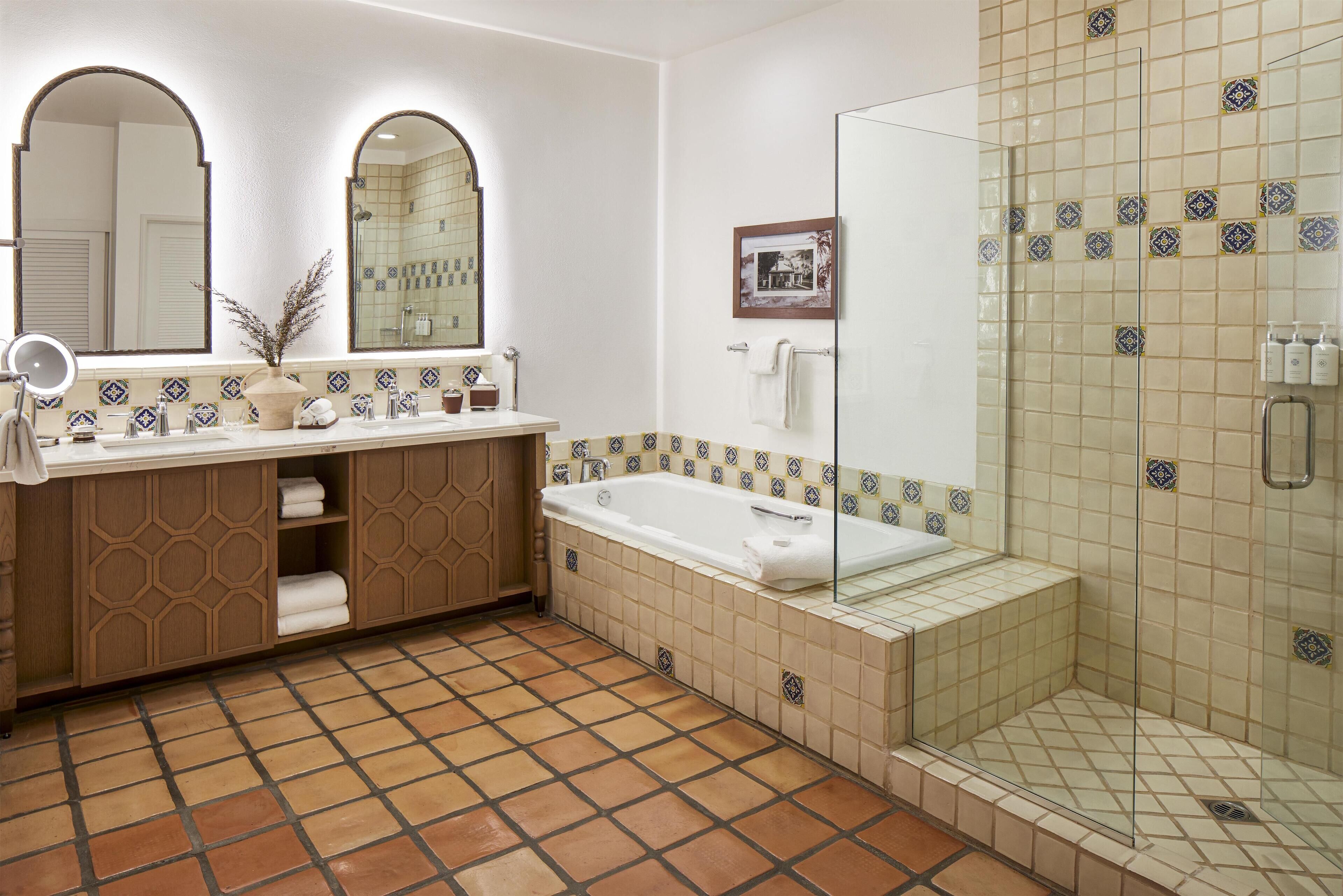 A bathroom with a bathtub, a shower, and a vanity with a mirror.