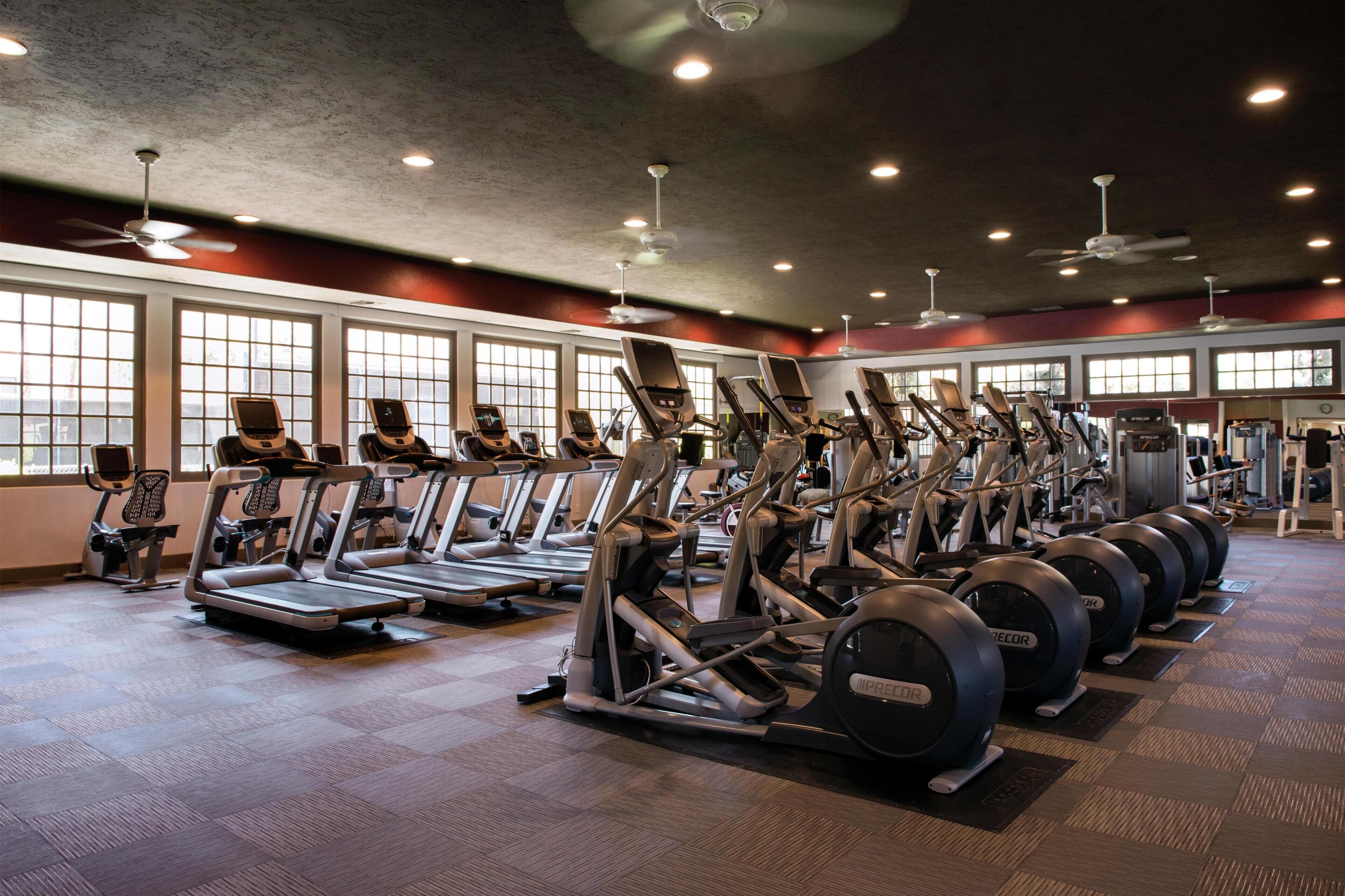 Une salle de sport équipée de tapis de course, de vélos elliptiques et d’appareils de musculation.
