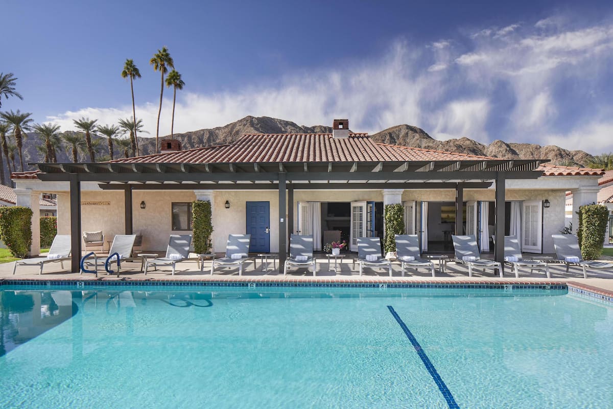 A poolside area with lounge chairs and a building with a tiled roof.