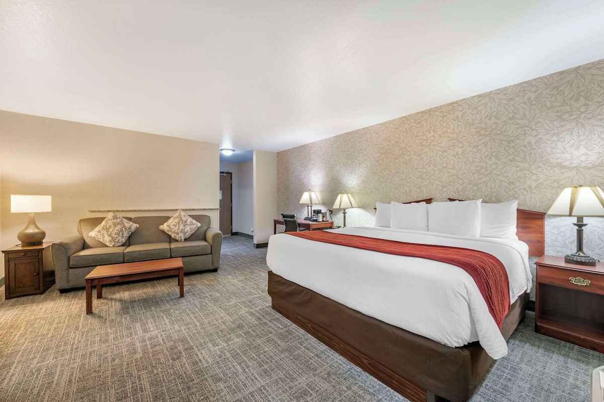 Ein Hotelzimmer mit einem großen Bett, einer Couch, einem Couchtisch und zwei Nachttischen mit Lampen.